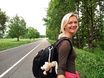 Portrait of female hiker with backpack while walking on country road