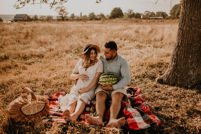 Portrait of smiling friends sitting on field