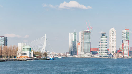 Sea by modern buildings against sky in city