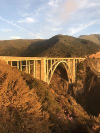 Bridge over mountain against sky