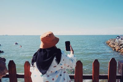 Rear view of woman looking at sea against clear sky