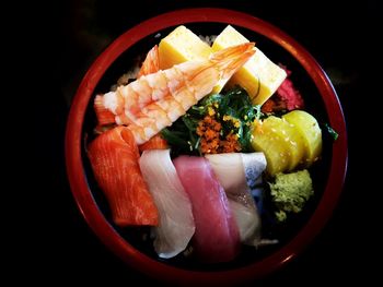 Close-up of fish and vegetables in bowl against black background