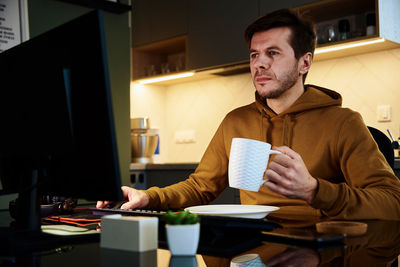 Tired man works late at workplace, use computer