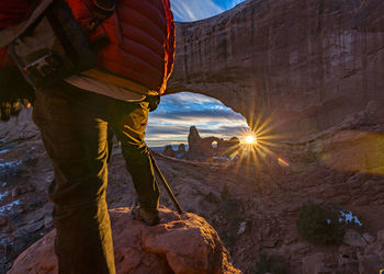 Man standing on rock against sky