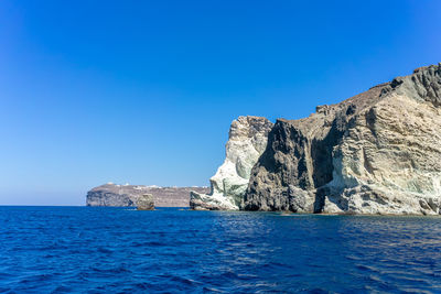 Face shaped rock on the blue sea against a blue sky. at akrotiri, santorini, cyclades, greece