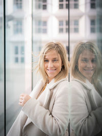 Portrait of smiling young woman against window