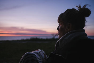 Portrait of woman looking at camera against sky during sunset