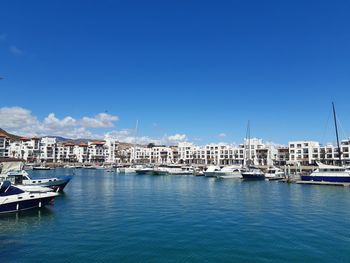 Sailboats moored at harbor against blue sky