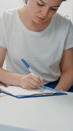 Midsection of woman writing in book