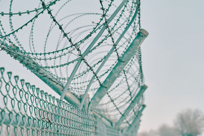 Low angle view of metal fence against sky
