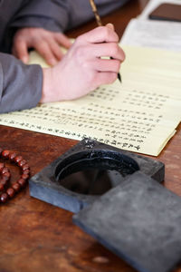 Cropped hand of person writing on paper at table