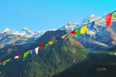 Multi colored flags on mountain against blue sky