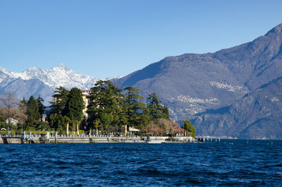 Scenic view of sea and mountains against clear blue sky