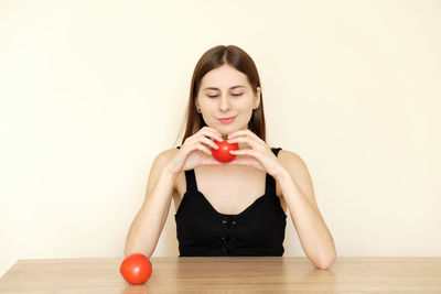 Portrait of young woman holding apple on table
