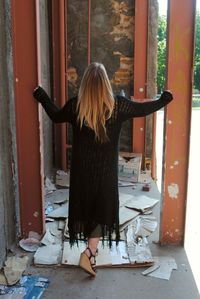 Rear view of young woman standing at abandoned building
