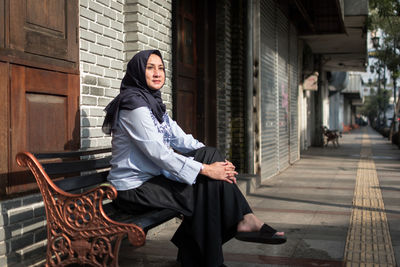 Woman in hijab sitting on bench