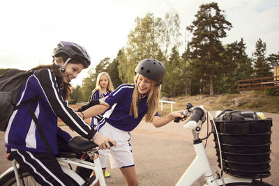 Cheerful friends enjoying with bicycle on footpath