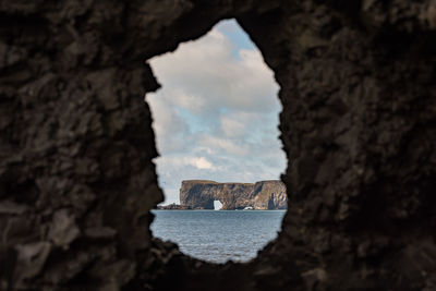 Rock formation by sea against sky