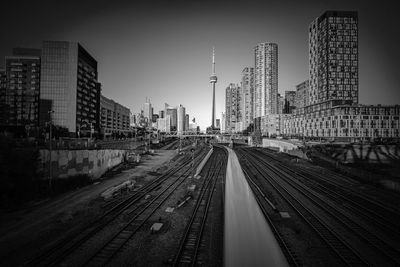 Railroad tracks amidst buildings in city against sky