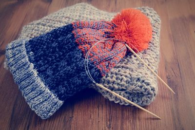 Close-up of knitting needles with hat and scarf on wooden table