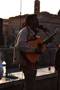 Man singing while playing guitar in city