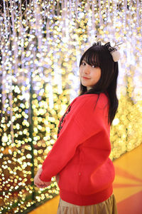 Young woman standing against christmas tree