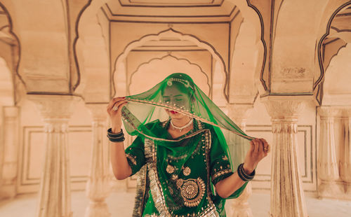 Midsection of woman holding her vail standing in corridor