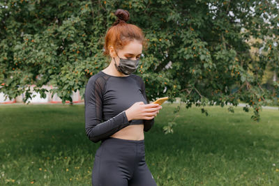 Portrait of young woman covering face and using mobile phone 