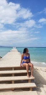 Full length of woman on beach blue sky blue swim suit 