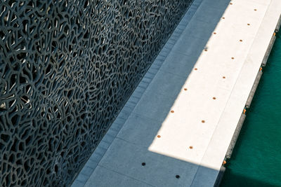 High angle view of shadow on footpath by wall