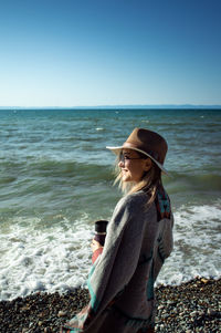 Young woman looking at sea against clear sky
