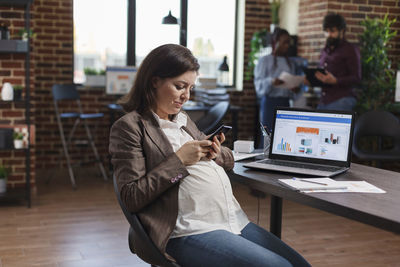 Pregnant businesswoman using mobile phone at office