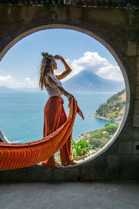 Side view of woman with arms outstretched standing in large window