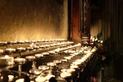 Illuminated votive candles by wall