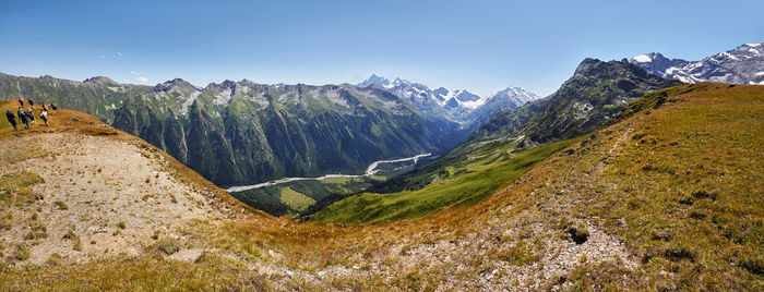 Panoramic view of rocky mountains against clear blue sky