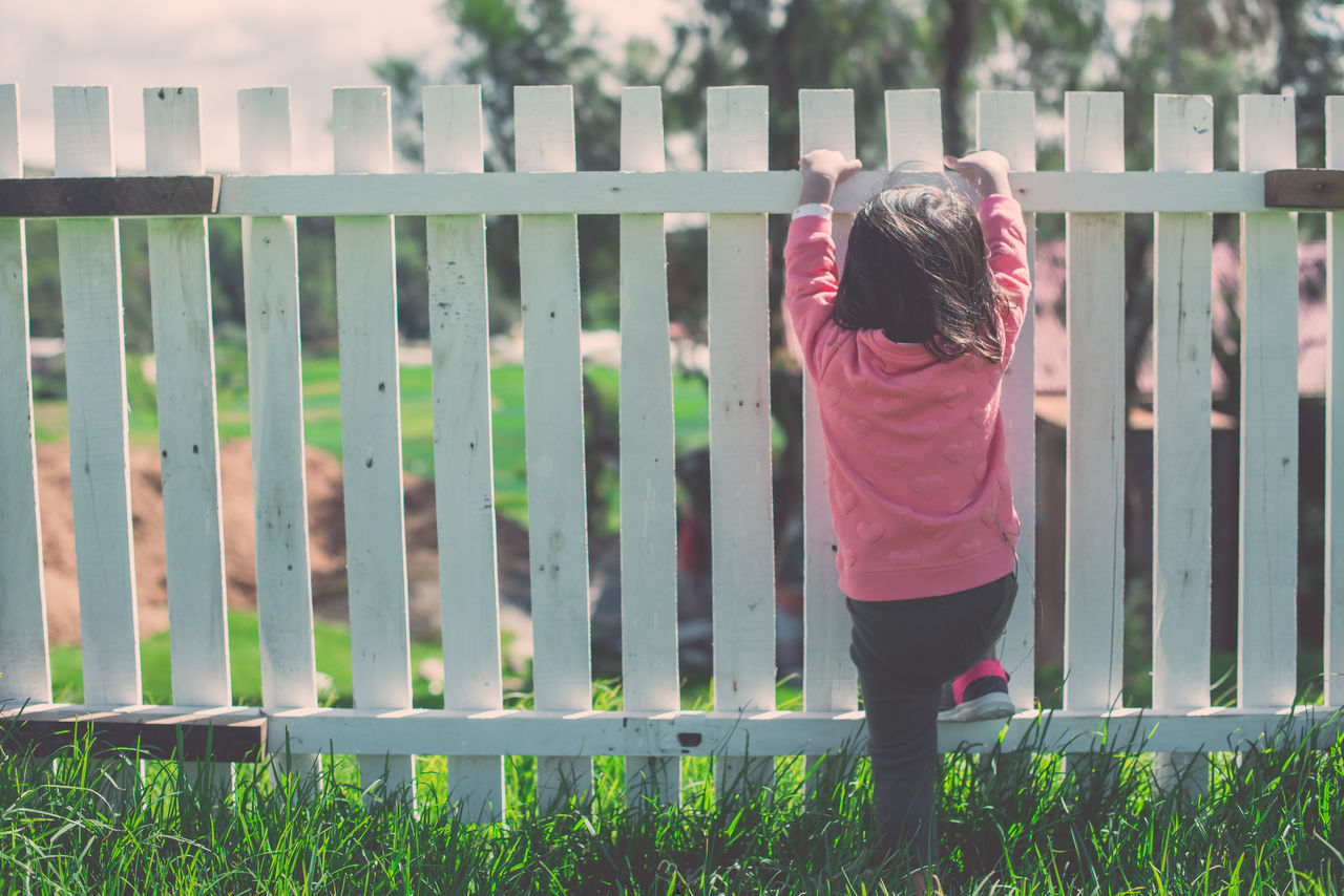 REAR VIEW OF WOMAN STANDING BY RAILING