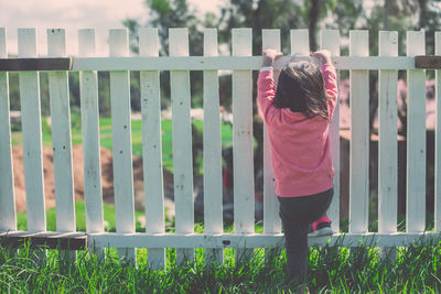 Rear view of girl standing by railing