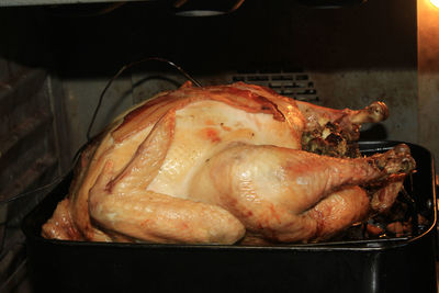 Close-up of roasted turkey in a roasting pan in the oven with an electric thermometer sticking out 