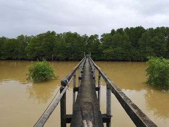 Footbridge over river against sky