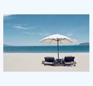 Deck chairs on beach against sky