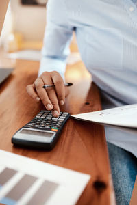 Midsection of man using calculator at table