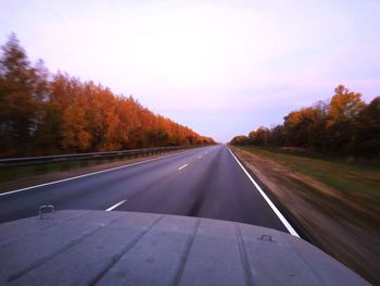 Road by trees against sky during autumn