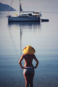 Rear view of woman wearing hat looking at view of sea