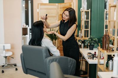 The makeup artist girl applies powder or blush to her client, completes the image. beauty