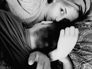 Portrait of young woman kissing boyfriend while lying on bed at home