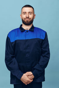 Portrait of young man standing against blue background