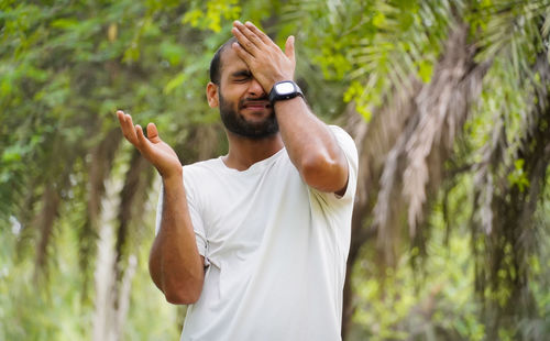 Side view of young man looking away while standing in forest