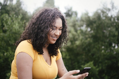 Young woman with curly hair using smart phone