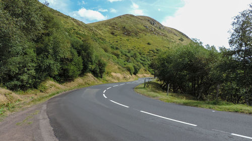 Road amidst green landscape against sky