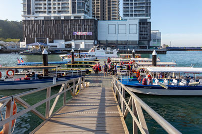 Boats in sea against modern buildings in city